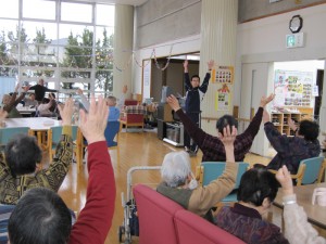入居者が手を上げてレクリエーション活動に参加している風景
